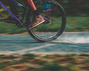 Cyclist riding a gravel bike on a scenic dirt road through rolling countryside