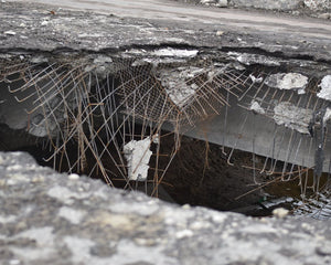 Large pothole in road surface showing exposed foundation and water damage during spring thaw season