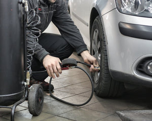Mechanic inspecting and adjusting tire pressure in an auto repair shop. Photo by Andrea Piacquadio on Pexels.