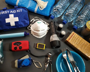 Essential emergency and safety supplies including first aid kit, flashlight, water, and tools laid out as a year-round car essentials checklist